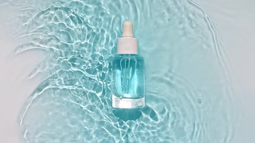 Dropper Bottle with Blue Liquid on Rippling Water
