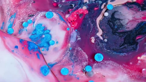 Colorful ink swirling in water with a vibrant mix of pink and blue tones, close-up