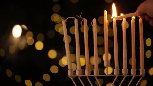 Lighting Hanukkah Candles with Warm Bokeh Background
