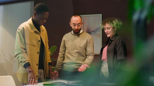 Young Man High-fiving Two Diverse Colleagues in Office