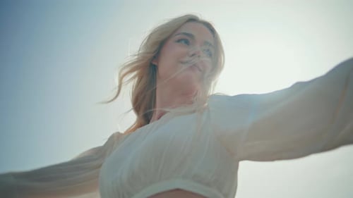 Blonde Woman Raises Arms in Joyful Fashion