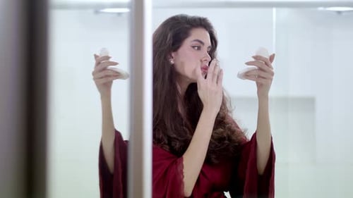 Woman Applying Cream to Face in Mirror