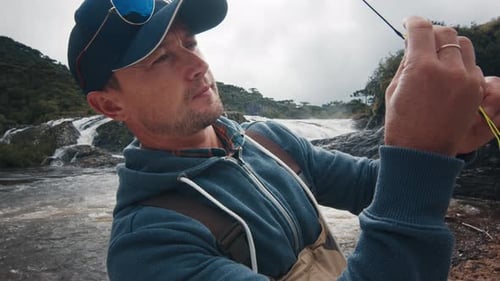 Man Fly Fishing By a Waterfall in Nature