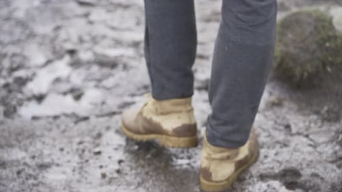Legs of Man in Hiking Boots Walking Through Mud