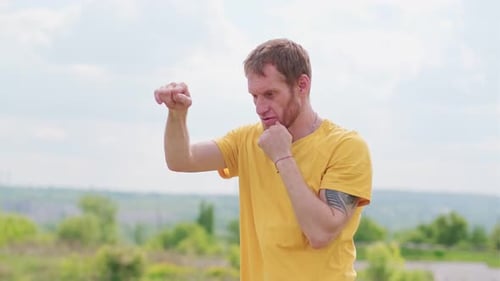 Man Practicing Boxing Moves in Scenic Park on a Sunny Afternoon