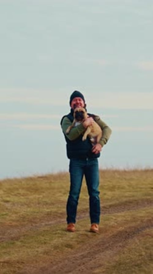 Man Holding His Dog On the Path