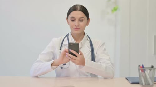Young Female Doctor Using Smartphone in Clinic