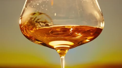 Orange or White Wine Bottle and Glass Against a Sunset in a Peaceful Vineyard Pouring of Ecological