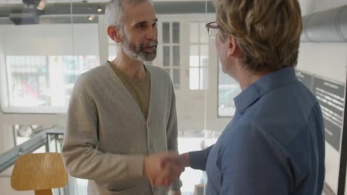 Senior Businessman Greeting Colleague with Handshake in Office