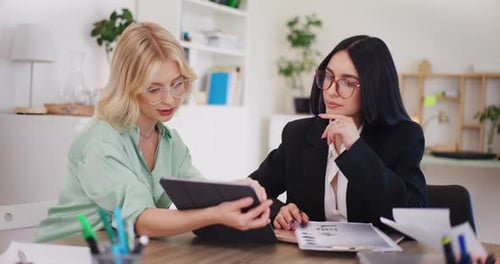 Businesswomen Collaborating on a Tablet in Modern Office