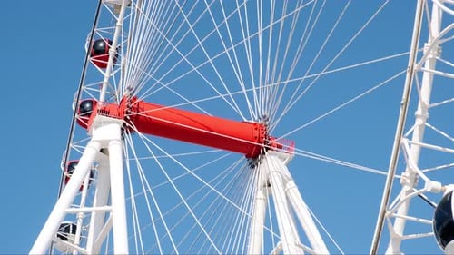 Large White Ferris Wheel Spins in Amusement Park Against Blue Sky