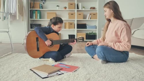 Child Learns Guitar with Adult Instructor Indoors