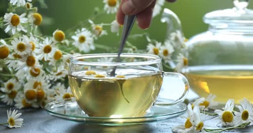 Chamomile Tea Being Stirred with Spoon on Table