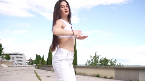 Energetic female dancer performing urban choreography in a city park