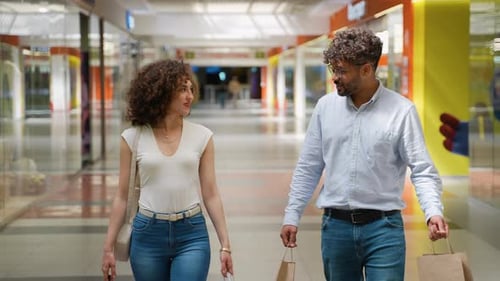 Happy Couple Walking in Mall Holding Shopping Bags