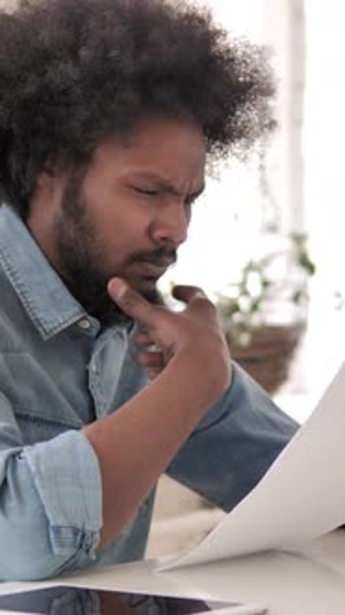 Man Reads Documents at Table, Thinking Deeply