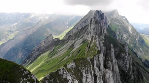 Aerial flyover over the side of Schafler ridge in Appenzell, Switzerland with cliffs, mountain peaks
