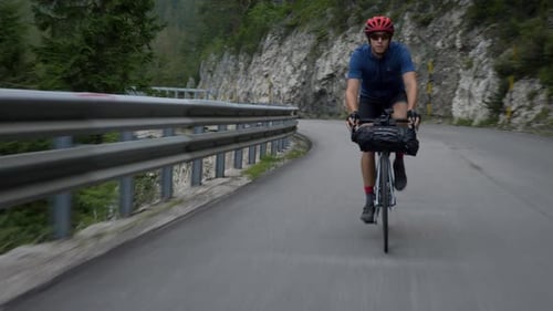 High speed chase, healthy man on a bicycle cycling through a mountain pass in the Dolomites, Italy