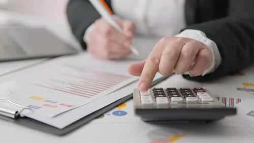 Adult Woman Using Calculator at Desk