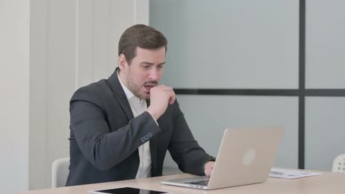 Man Coughing While Working at His Laptop