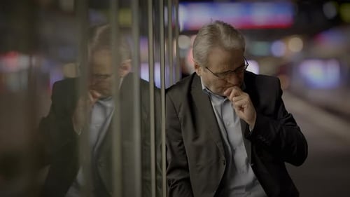 Mature Man Leaning Against Mirrored Wall in City