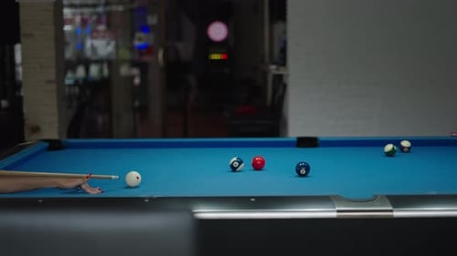 Frau spielt Billard beim Schlagen des Spielballs mit einem Snooker-Queue auf dem Tisch