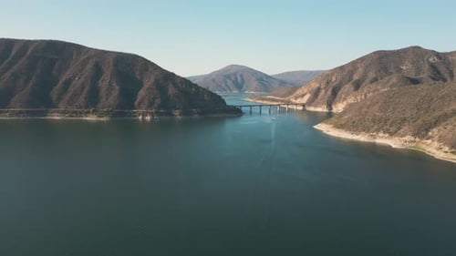 Aerial drone flying over a lake, water dam, with mountains at sunrise. Beautifull dreamy landscape v
