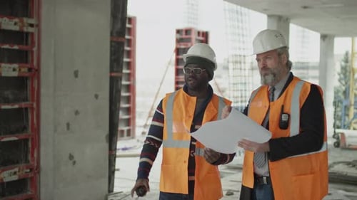 Construction Managers Discussing Blueprints on Building Site