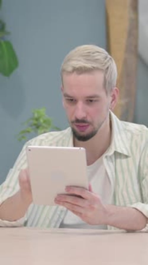 Man With Blonde Hair Uses Tablet and Celebrates