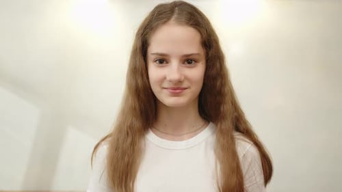 Portrait of young girl 12 years old with long hair smiling looking at camera indoors close-up