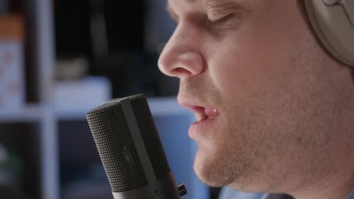 Close Up View of Microphone and Face of Man in Blue Shirt Singing in Recording Studio Professional