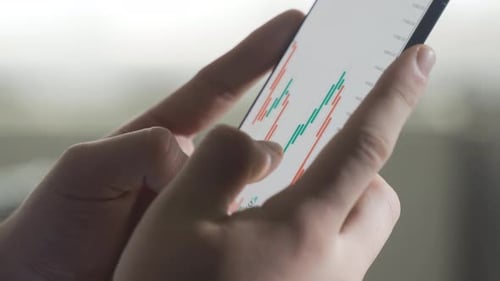 En regardant le marché boursier, les actions, les graphiques d'investissement au téléphone, en gros plan.