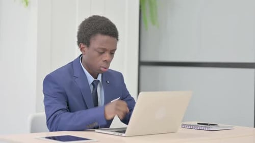 Man Working on Laptop Coughing in Office