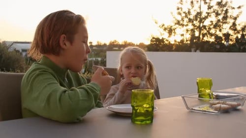 Children Eating Pastries Outdoors at Sunset