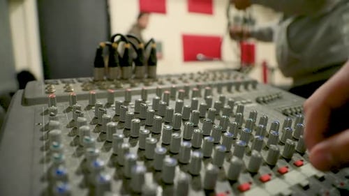Close-up of a man tuning the audio mixer in the studio