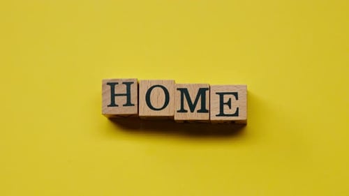 Wooden Blocks Spelling Home on Yellow Background