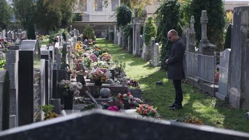 A Man Paying His Respects at a Cemetery Captured in a Solemn Moment Amongst the Graves