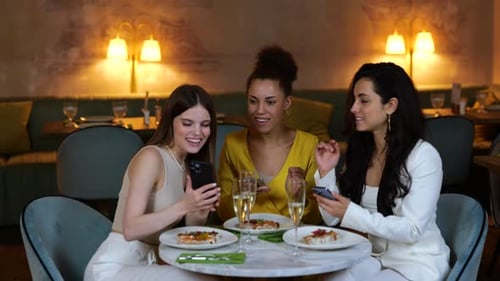 Happy Pretty Lady Sitting in the Restaurant While Showing Smartphones Screen for Her Best Female