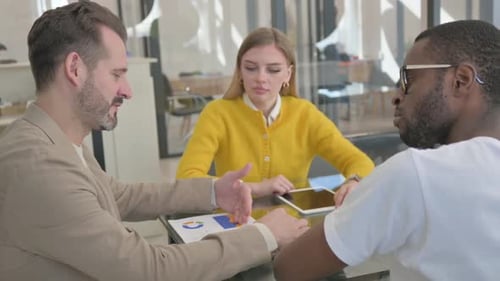 Three Colleagues Discuss Business at Modern Table