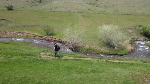 Man Walking by Stream in Rural Area