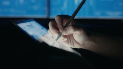 Hand Using Stylus on Tablet with Charts