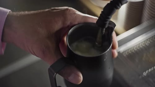 Hand Frothing Milk in Black Metal Mug