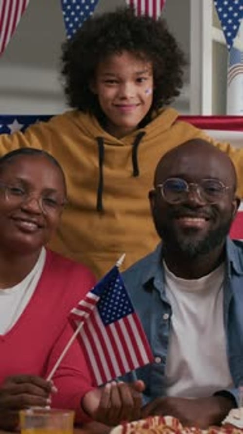 Happy Family Posing with American Flags Indoors
