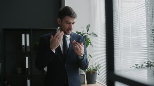 CEO Talking on Speakerphone during Workday in Office