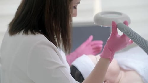 Woman Receiving Skincare Treatment with Magnifying Lamp