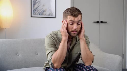 Adult Man Suffering from Headache on Sofa