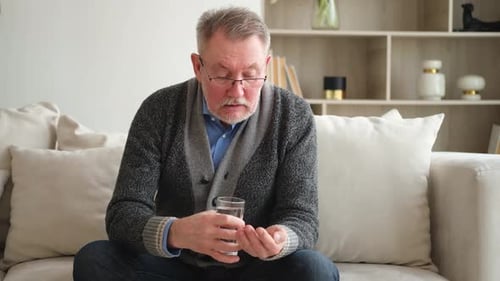 Senior Man Taking Pills with Water Indoors