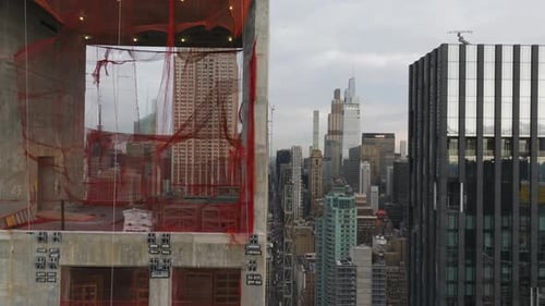 Luftaufnahmen zeigen eine Baustelle, die mit leuchtend orangefarbenen Sicherheitsnetzen geschmückt ist, mit neuen