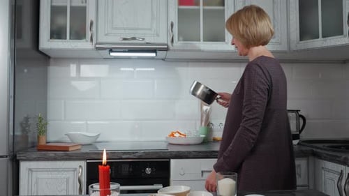Woman Cooking Meal in Kitchen with Lit Candle