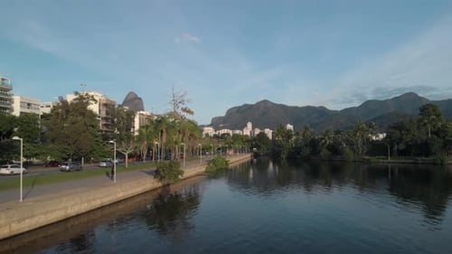 Panorâmica aérea para trás ao lado do lago da cidade do Rio de Janeiro com pessoas fazendo seu ex matinal